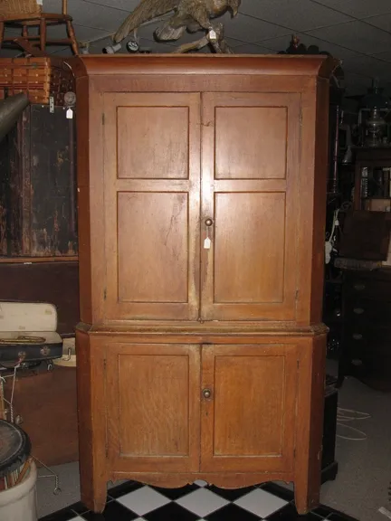 Walnut Corner Cupboard. First quarter 19th Century. Two-piece, later 19th Century faux grain paint. Top consisting of two raised panel doors, crowned with simple cover cornice. Base with two rasied panel doors on high leg with graceful skirt. Popular secondary.